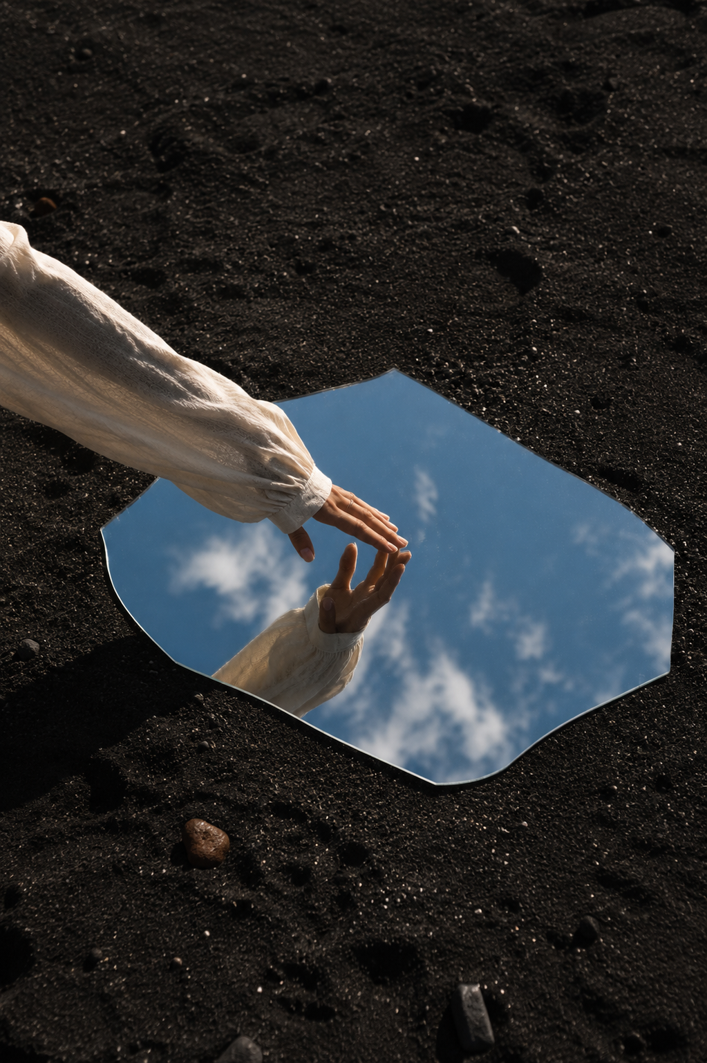 Reflejo de manos sobre arena volcánica